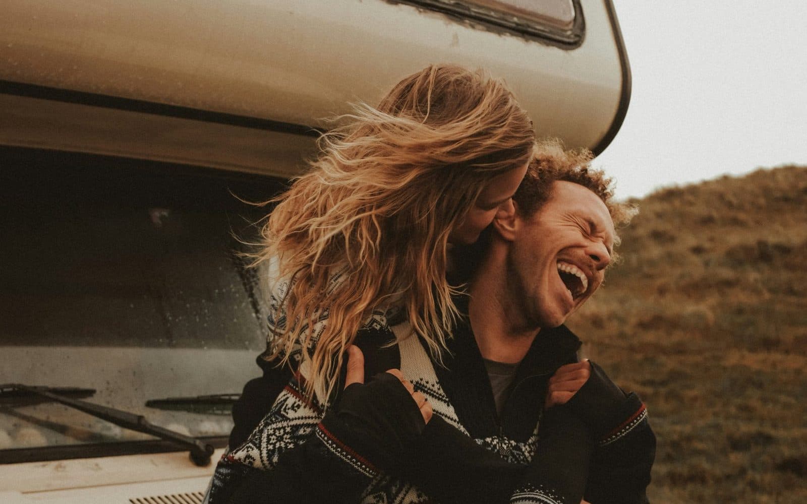 Un couple qui rit devant son camping-car