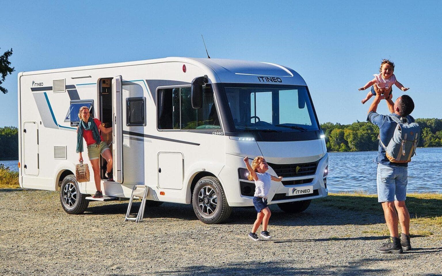 Une famille qui joue devant son camping-car, au bord d'un lac